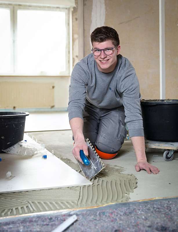 Carl Mies trägt Fliesenkleber auf den Boden auf - Traumberufe Fliesen-, Platten- und Mosaikleger 2023
