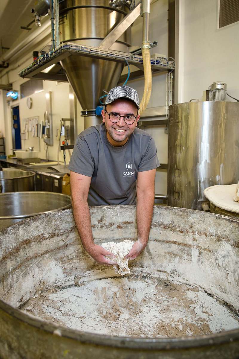 Ayoub Rabah nimmt Sauerteig aus dem riesigen Bottich - Traumberufe Bäcker, Konditor und Fachverkäufer im Lebensmittelhandwerk 2023