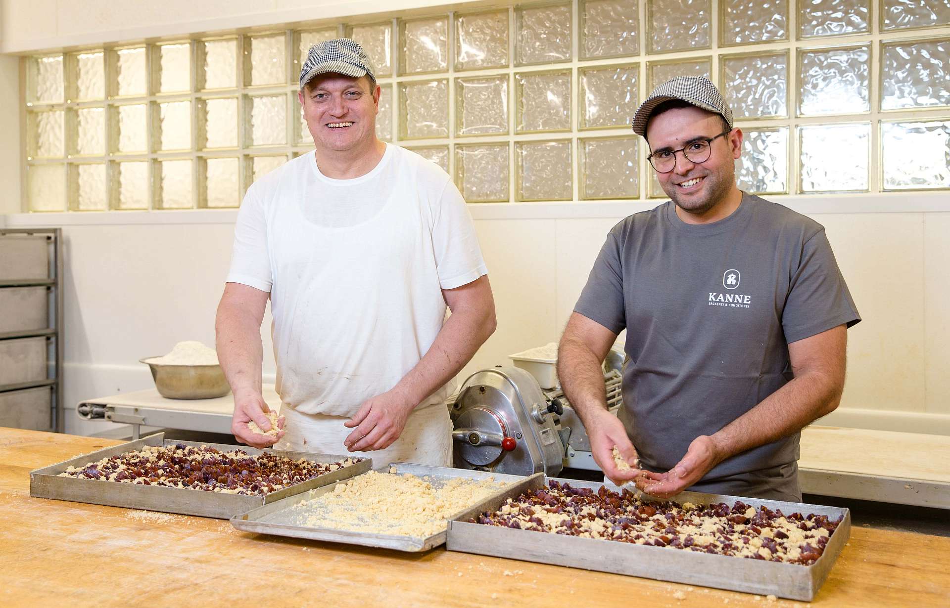 Ron Pieper und Ayoub Rabah bestreuen den Zwetschgenkuchen mit Butterstreuseln - Traumberufe Bäcker, Konditor und Fachverkäufer im Lebensmittelhandwerk 2023