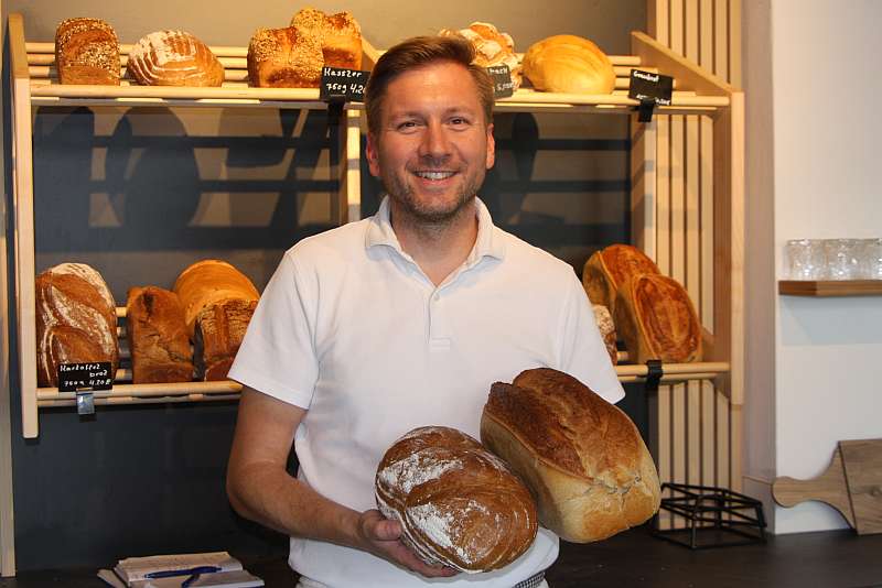 Bäckermeister Benjamin Redder hält zwei Brotsorten in der Hand - Traumberufe Bäcker, Konditor und Fachverkäufer im Lebensmittelhandwerk 2023