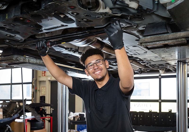 Dylan Malik Ochi zieht unter einem Auto eine Schraube nach - Ausbildung Kfz-Mechatroniker 2024 Soest