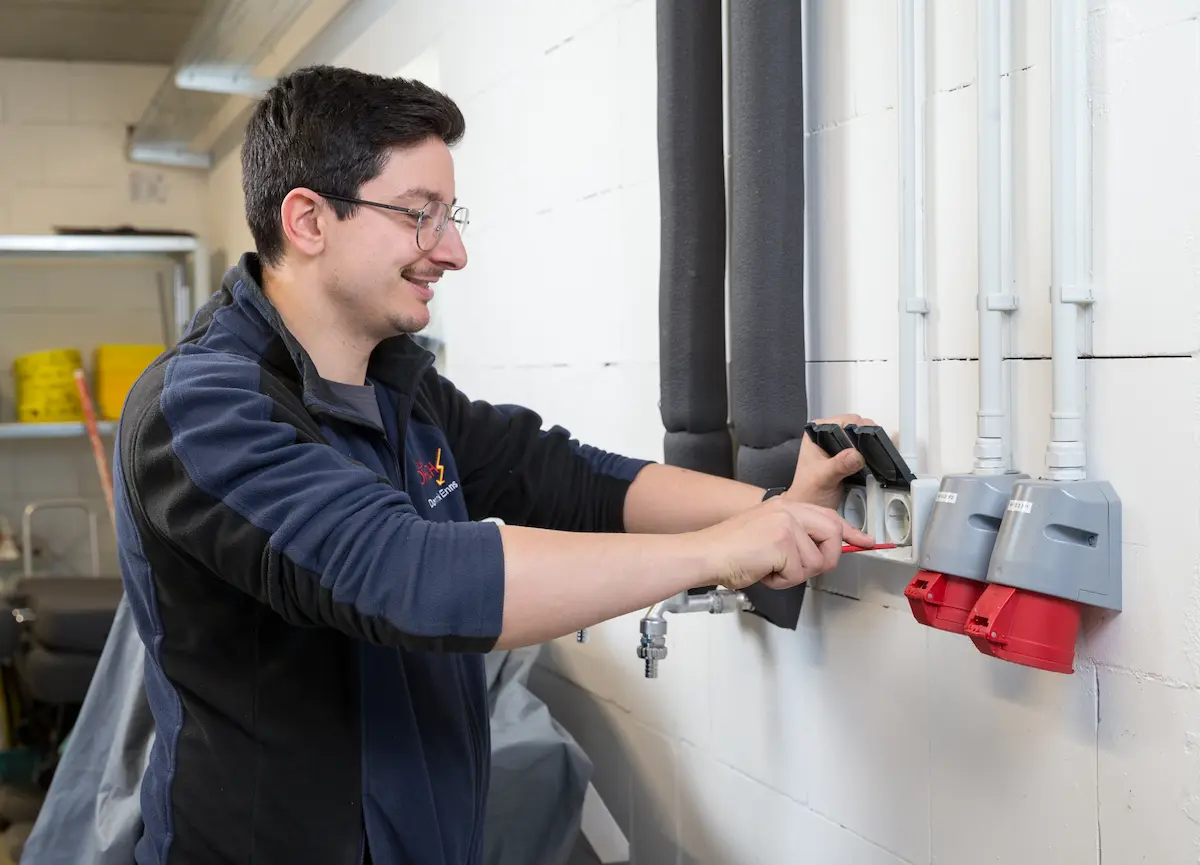 Dominik Enns montiert eine Steckdose in einem Lager - Traumberufe 2026 Elektroniker