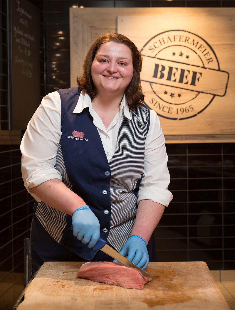 Antonia Mudra schneidet ein Stück Fleisch auf einem traditionellen Holzblock - Traumberufe Fleischer 2023