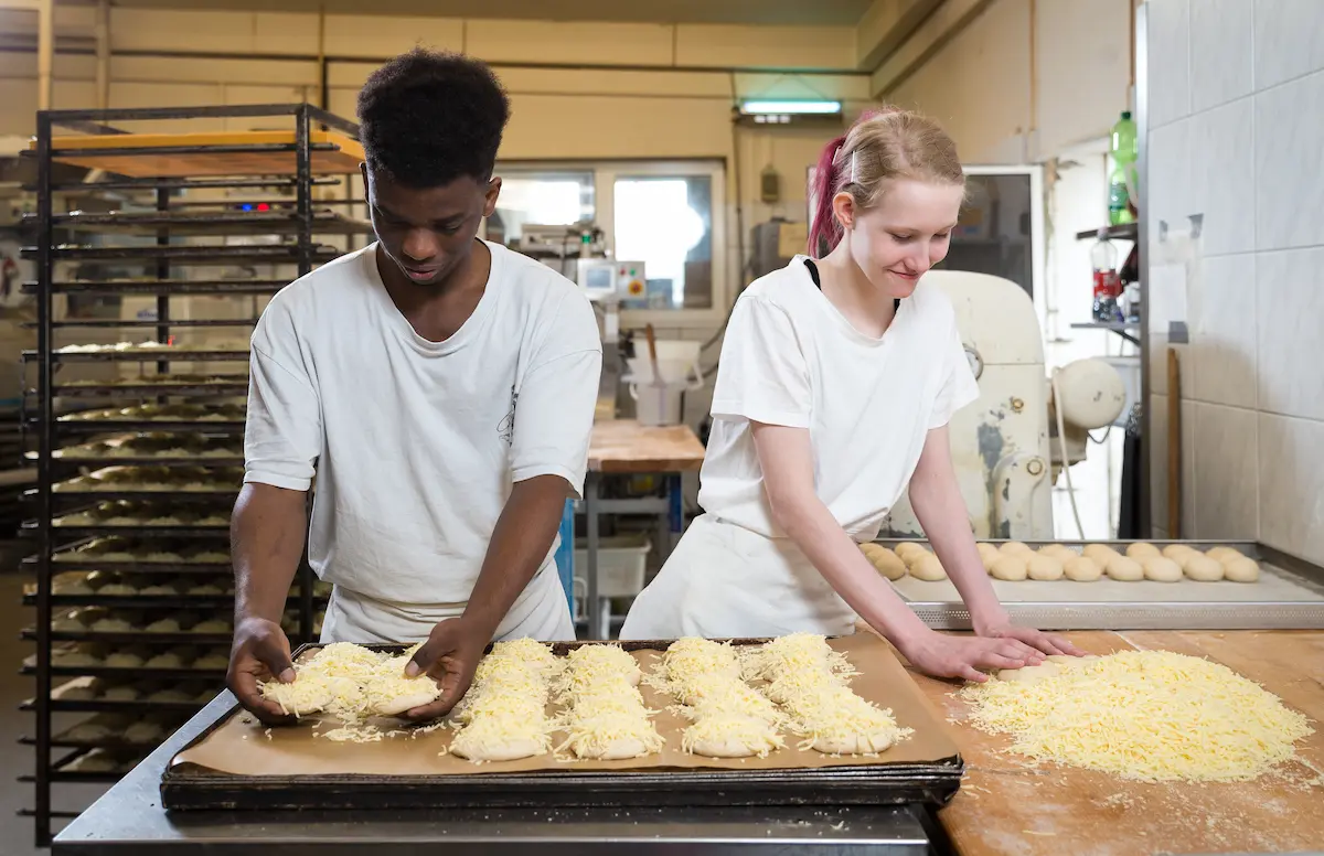 Anna Brinkmann und Amadou Bah bereiten Käsebrötchen für den Ofen vor. Traumberufe Bäcker und Konditor 2026