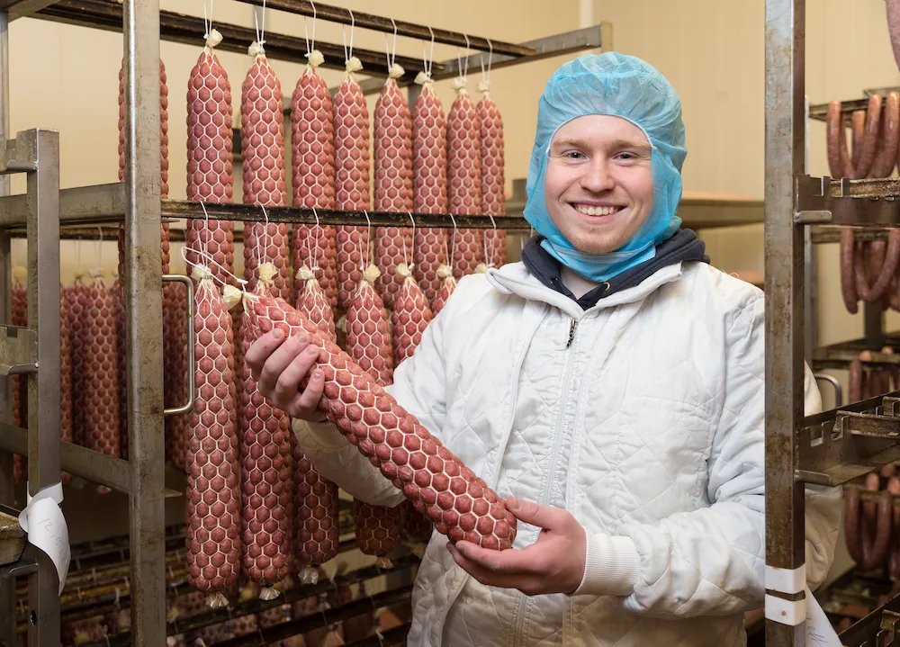 Die Blümchen-Salami, die der 20-jährige Fleischer-Azubi Erik Sterkel in den Händen hält, ist einer der Klassiker der Fleischerei Schäfermeier.