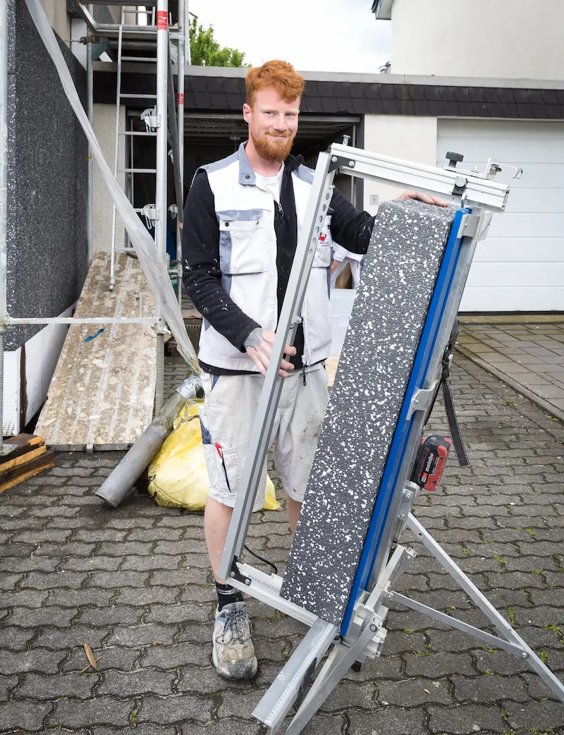 Nico Stoof schneidet eine Styroporplatte für das Wärmedämmverbundsystem an einem Einfamilienhaus auf Maß. Traumberufe Maler 2026