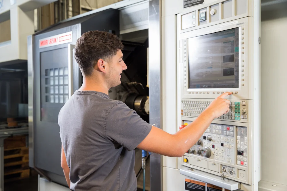 Zerspanungsmechaniker und Ausbilder David Bellavona programmiert das CNC-Bearbeitungszentrum, das über eine vollautomatisierte Portalbeladung verfügt, für einen Kundenauftrag.