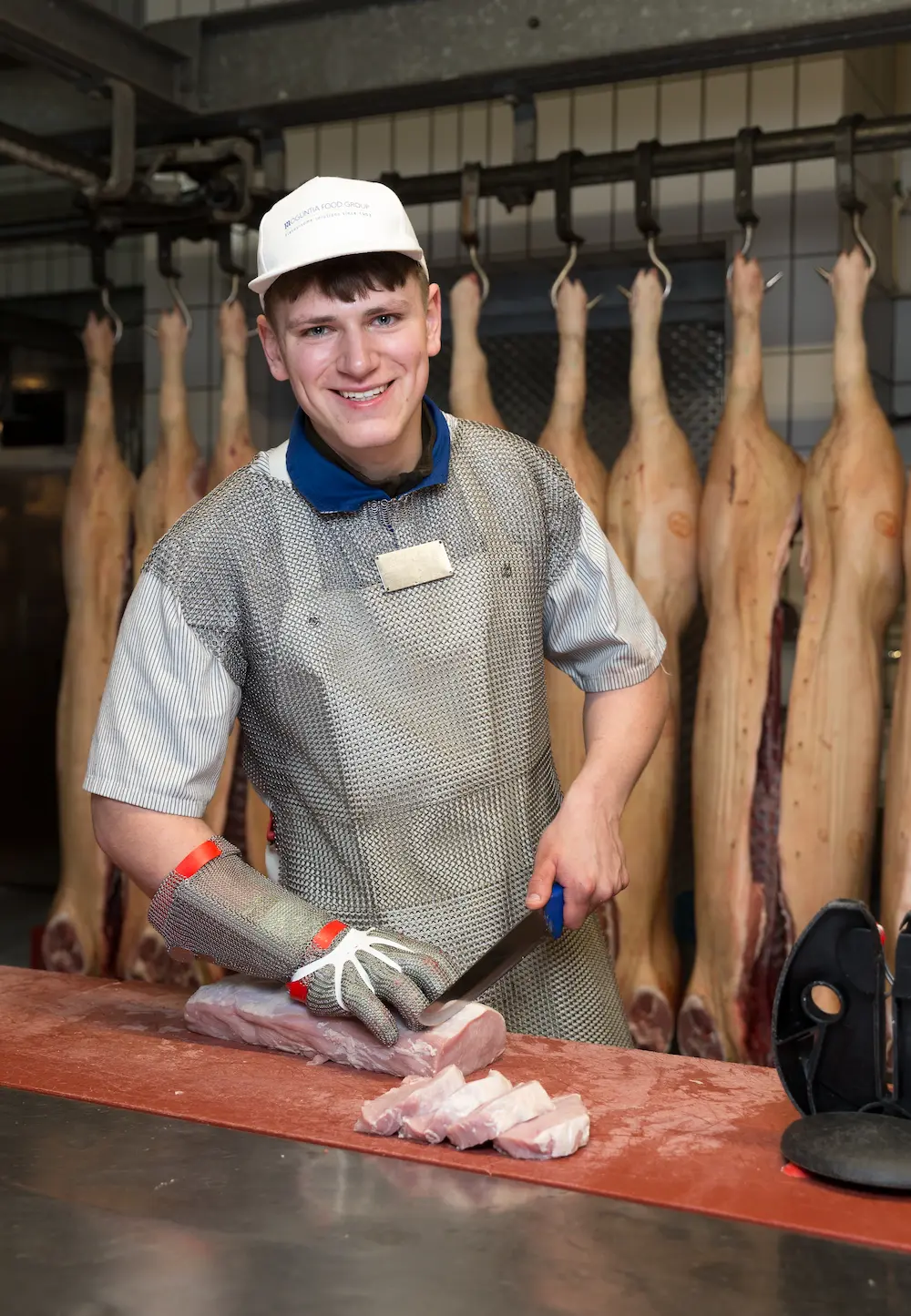 Mit einem Zuschneidemesser schneidet der angehende Fleischer Lorenz Baumüller Schnitzel. Zum Schutz vor Schnittverletzungen trägt der 19-Jährige eine Stechschutzschürze und einen Kettenhandschuh.