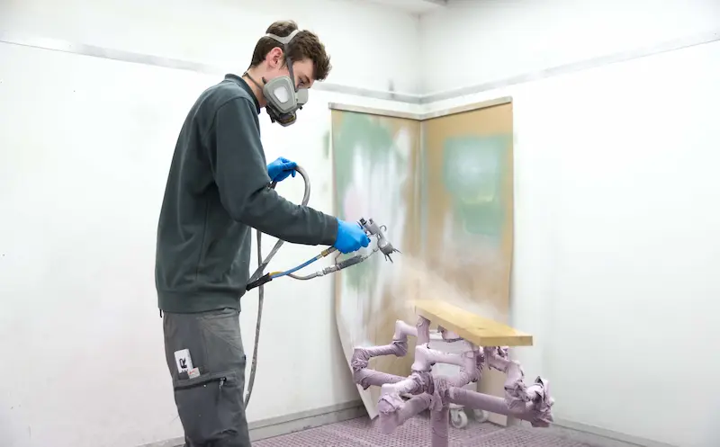 Jannis Gerke trägt Klarlack auf ein Holzbrett auf. Traumberufe 2026 Tischler