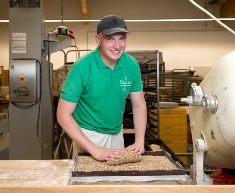 Sven Schiller w&auml;lzt vor dem Backen das Brotteig in Haferflocken. Traumberufe B&auml;cker und Konditor 2026