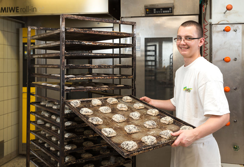 Steffan Weiß hält ein Blech mit frisch vorbereiteten Brötchen für den Backofen - Traumberuf Bäcker 2025