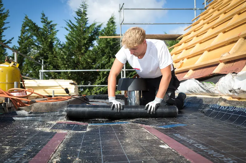 Leon Vanderstuyf rollt Schweißbahnen über ein Flachdach aus. Traumberufe Dachdecker 2026