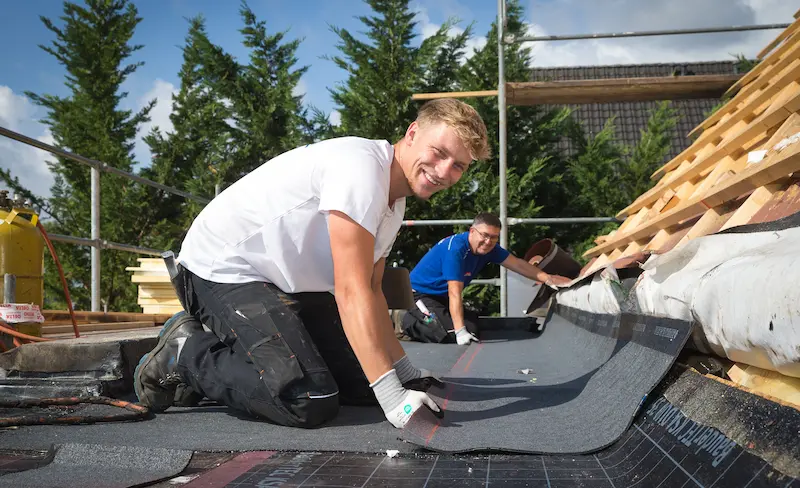 Leon Vanderstuyf und Jahir Krasniqi bauen eine Feuchtigkeitssperre am Übergang zwischen Steil- und Flachdach ein. Traumberufe Dachdecker 2026