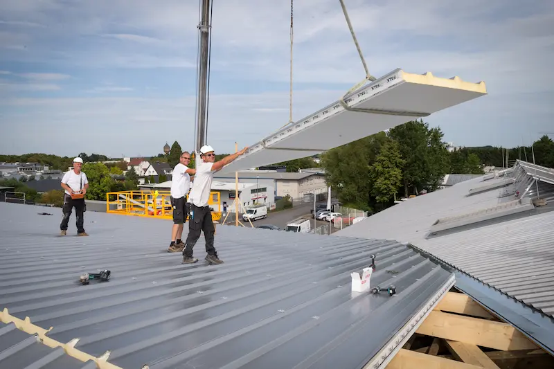 Dachdecker heben mit einem Kran Bauelemente aufs Dach. Traumberufe Dachdecker 2026