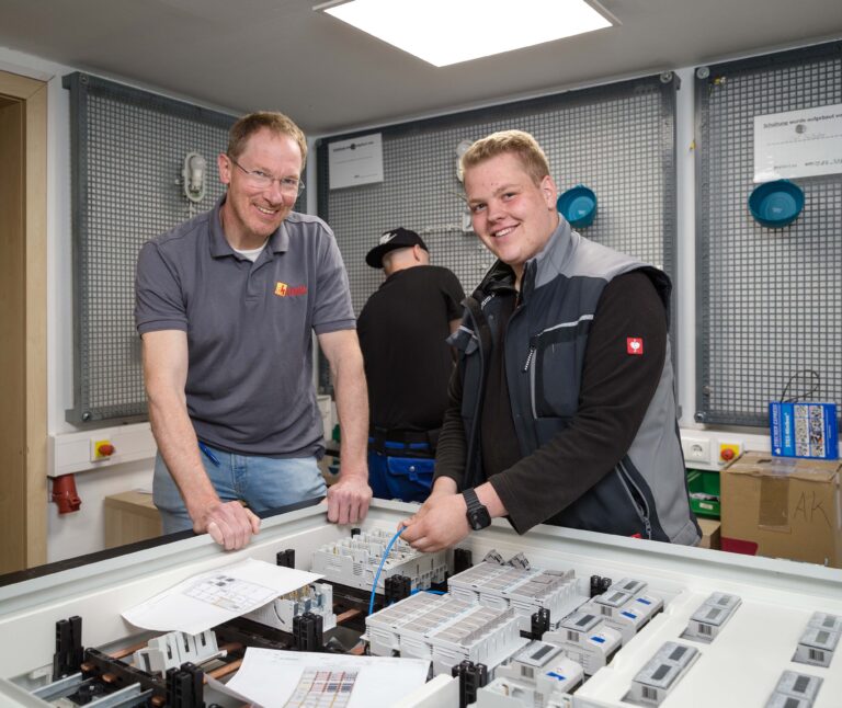 Elektroniker-Azubi Mika Ferber (rechts) überprüft gemeinsam mit Elektrotechnikermeister Andreas Schmidt die Kabel in einem Schaltschrank, der einige Tage später an einen Kunden ausgeliefert werden soll. Foto: Gabi Bender