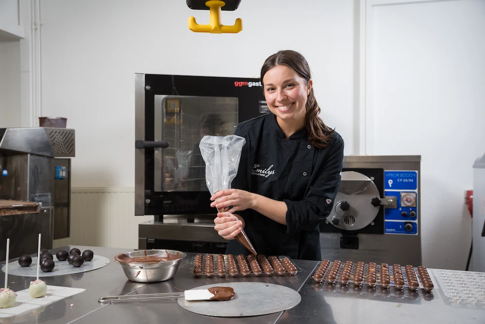 Nachdem das Füllen der Pralinen beendet ist, verschließt Jana Graute die Öffnung mit Schokolade.