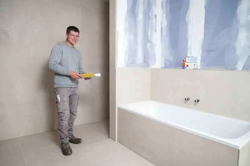 Carl Mies steht in überprüft ein frisch gefliestes Badezimmer. Traumberufe Fliesenleger 2026
