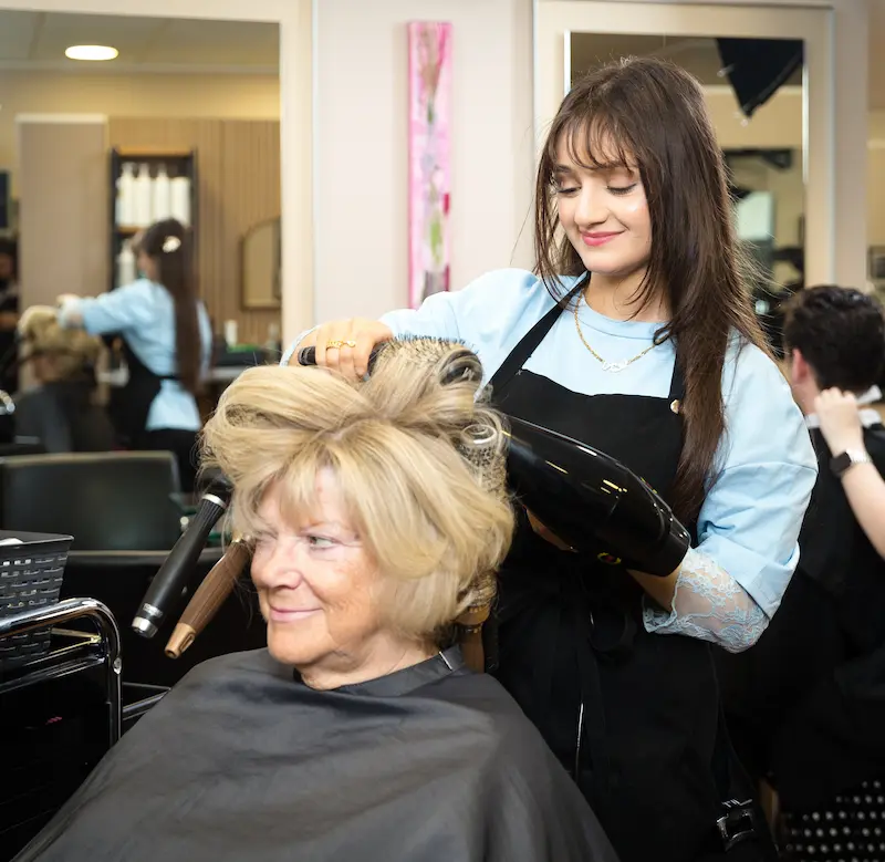 Nor Ali föhnt und frisiert die Haare von Kundin. Traumberufe Friseur 2026
