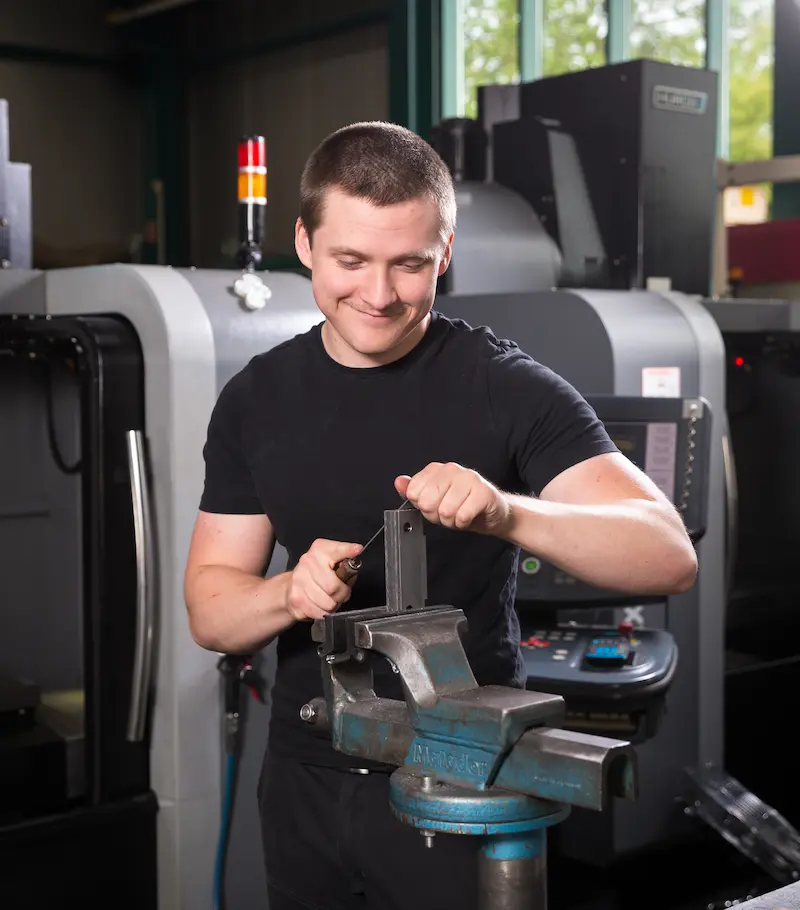 Mit einer Flachfeile entgratet Azubi Louis Rochna ein Werkstück und entfernt so scharfe Kanten und Materialüberstände. Traumberufe Feinwerkmechaniker 2026