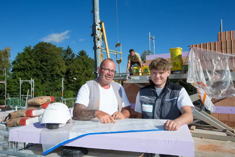 Oliver "Olli" Dünnebacke (links) zeigt dem Azubi Max Yanik eine Besonderheit auf dem Bauplan eines Einfamilienhauses. Traumberufe Maurer 2026
