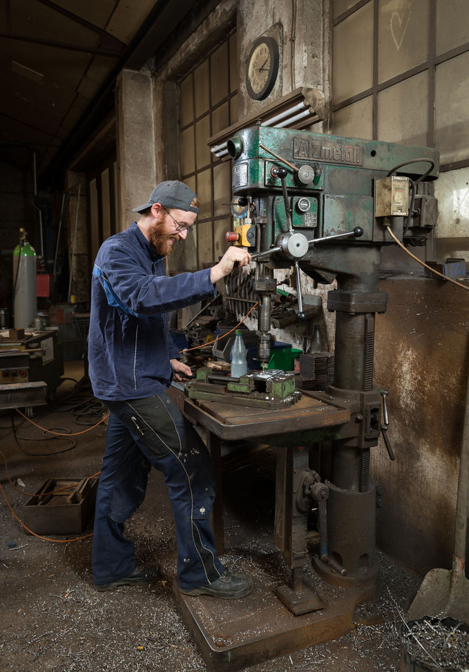 Mit der Standbohrmaschine bohrt Metallbauer-Azubi Daniel Korcz ein Loch in ein Werkstück - Traumberuf Metallbauer 2025
