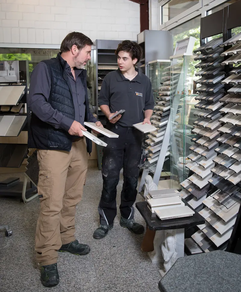 Im Showroom wählen Steinmetz Karsten Schütte (links) und sein Sohn, Steinmetz-Azubi Christian Schütte, das Material für eine Arbeitsplatte aus. Traumberufe Steinmetz 2026