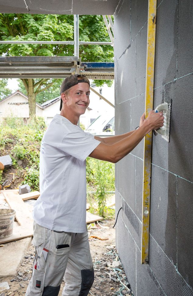 Tim Lukowicz hält eine Wasserwaage gegen die Wand - Traumberuf Stuckateur 2025