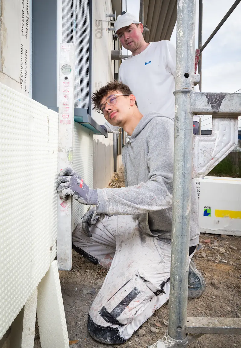 Stuckateur Hubert Graf beobachtet, wie Azubi Magnus Kipping die richtige Lage einer Styroporplatte prüft. Traumberufe Stuckateur 2026