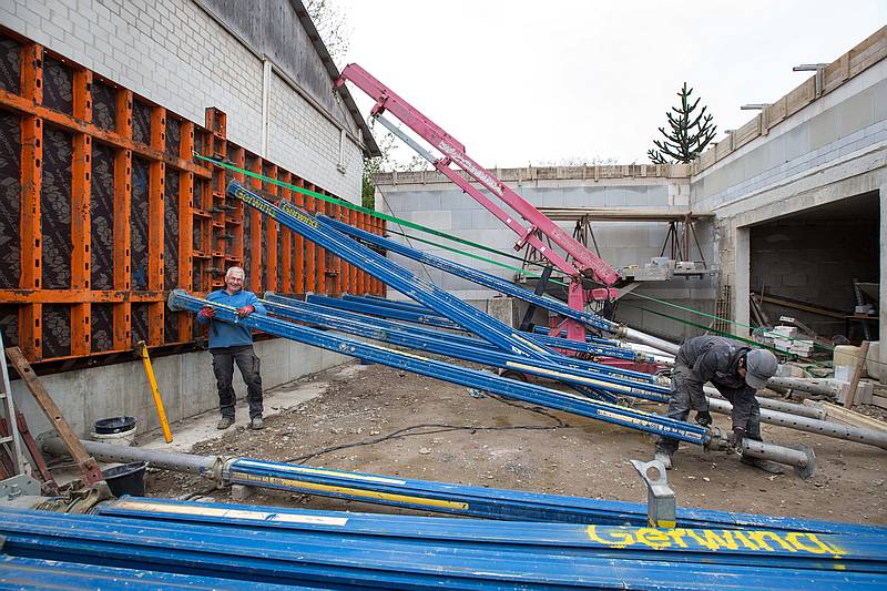 Mit diesen Deckenstützen aus Aluminium, die sich bis auf 8,50 Meter ausziehen lassen, übertragen Geschäftsführer Klaus-Dieter Haase (links) und sein Mitarbeiter Wahdatullah Nasery den Druck der einhäuptigen Schalung auf das Fundament der gegenüberliegenden Garage. Foto: Gabi Bender
