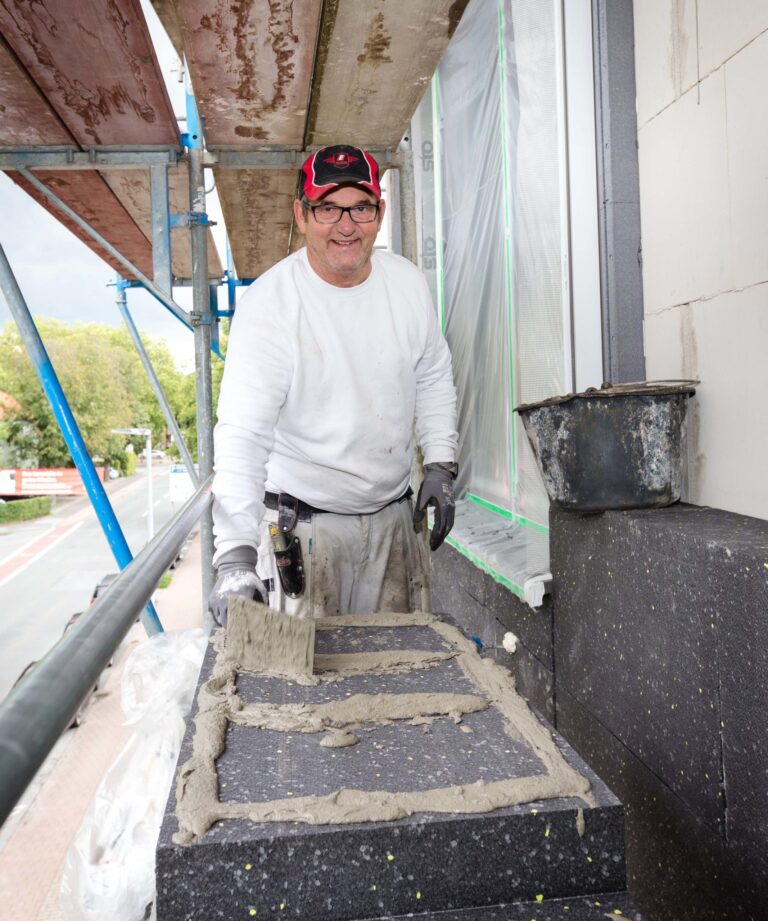 Stuckateur Frank Gernhard trägt Klebemörtel auf einer Wärmedämmplatte auf, damit diese optimal an der Wand haftet.
