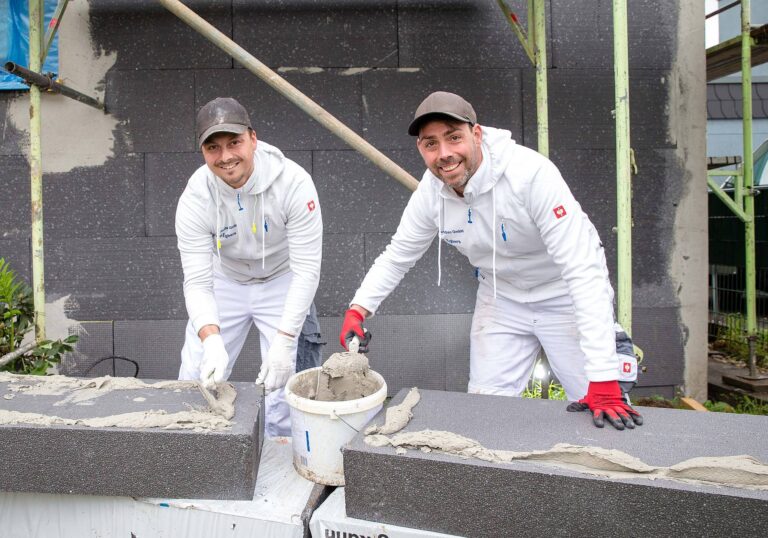 Rene (links) und sein Bruder Manuel Egbers bringen Armierungskleber auf zwei Dämmplatten eines Wärmedämmverbundsystems auf. Foto: Gabi Bender