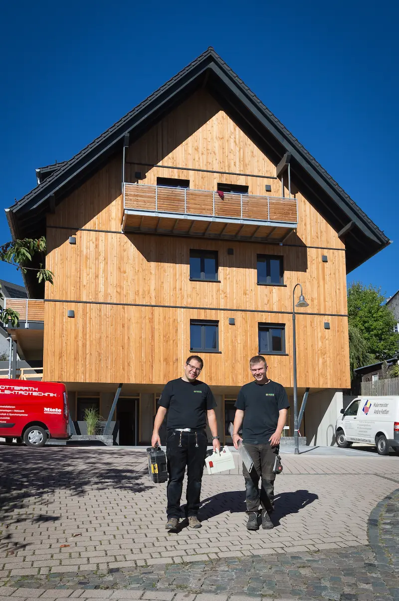 Zimmerermeister Christian Hüske (links) und sein Azubi Luca Köster vor einem frischgebauten Haus aus Holz. Traumberufe Zimmerer 2026