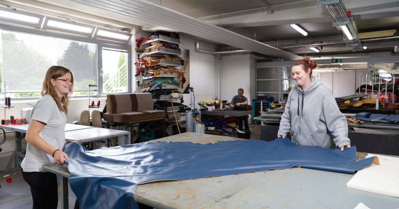Nina Höweler und Wendy Grefe bearbeiten große Lederteile - Traumberufe Raumausstatter, Sattler und Schneider 2023