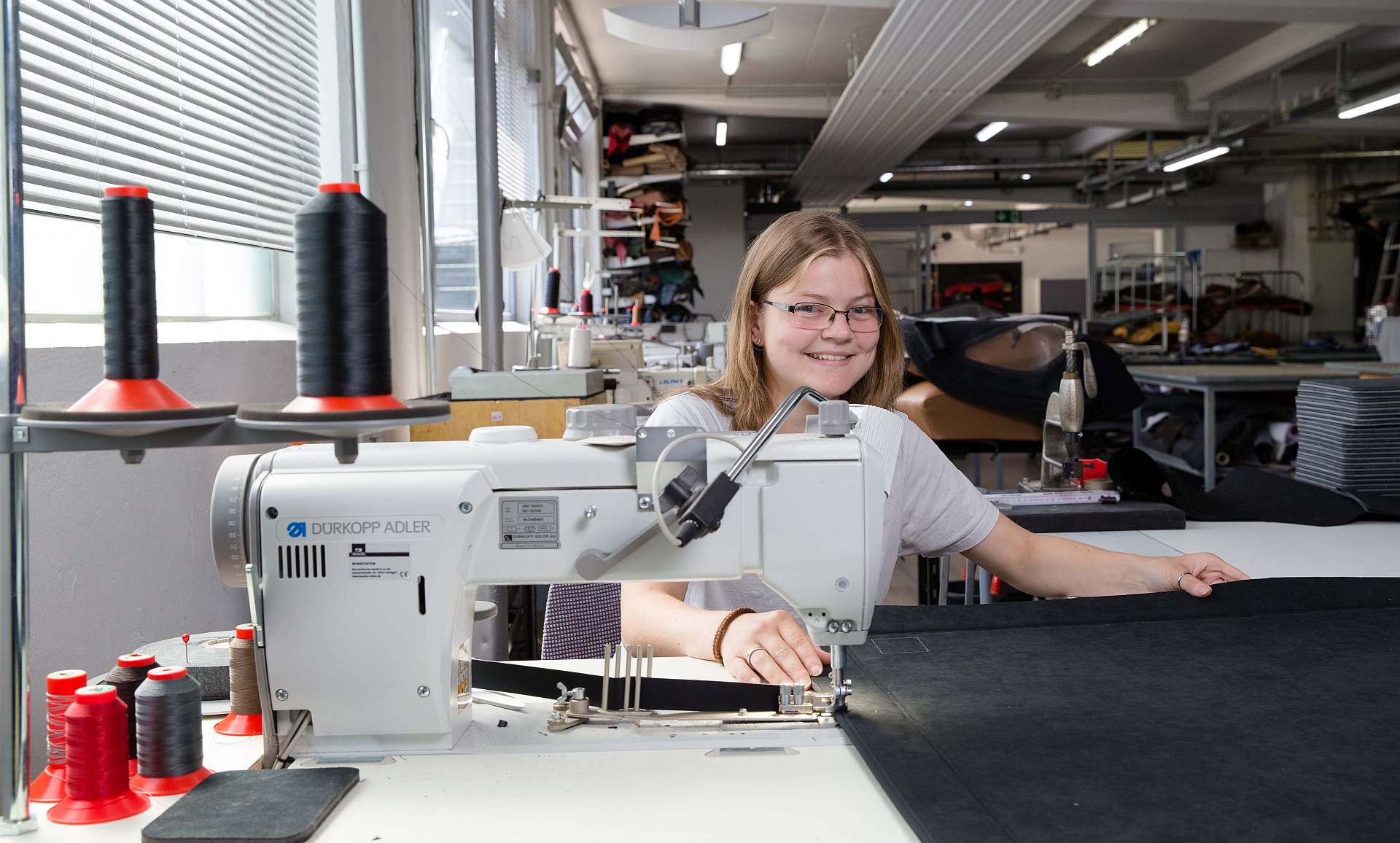 Auszubildende Nina Höweler arbeitet mit professionellen Industrienähmaschinen - Traumberufe Raumausstatter, Sattler und Schneider 2023