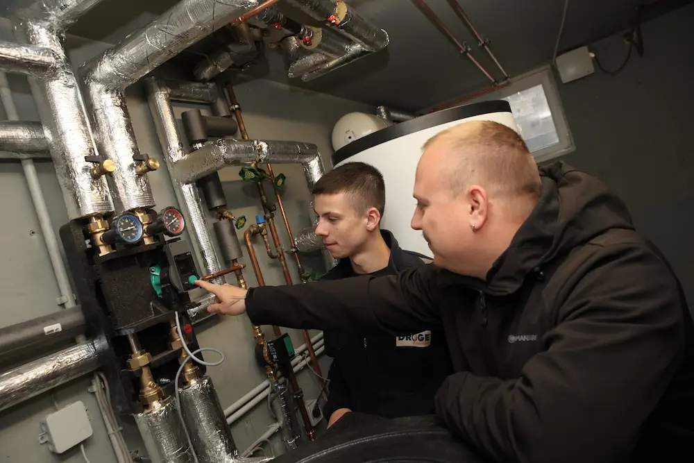 Lukas Hartke stellt das Heizsystem ein, Meister Jan Schaefer (rechts) kontrolliert. Traumberufe 2026 Anlagenmechaniker für SHK