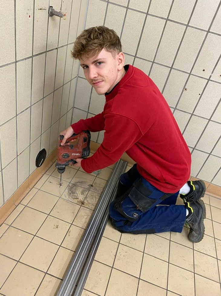 Ben Kattenbusch bohrt in die Fliese am Boden - Traumberuf Sanitär 2025