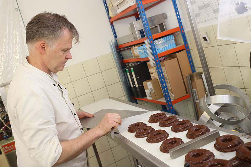 Bäcker- und Konditormeister Andreas Potthoff hebt vorsichtig frisch gebackene Süßwaren von dem Untergrund auf- Traumberufe Bäcker, Konditor und Fachverkäufer im Lebensmittelhandwerk 2023