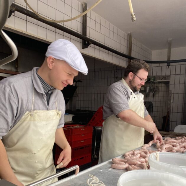 Die Azubis Philipp Klekler (vorn) und Sanel Mattiebe bei der Bratwurstproduktion. Foto: Christoph Steinigner