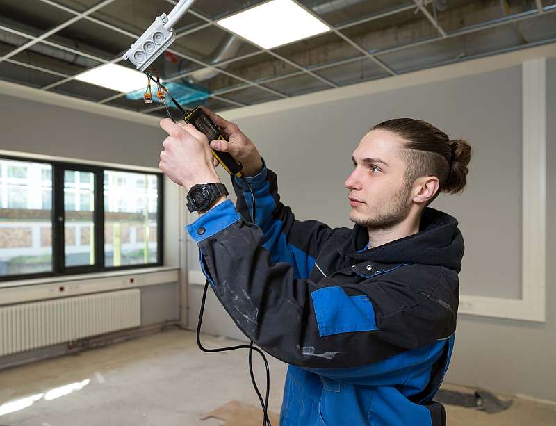 Der Auszubildende Torben Brinkmann überprüft die Spannung an neuen Lampen - Traumberufe Elektroniker und Informationselektroniker 2023