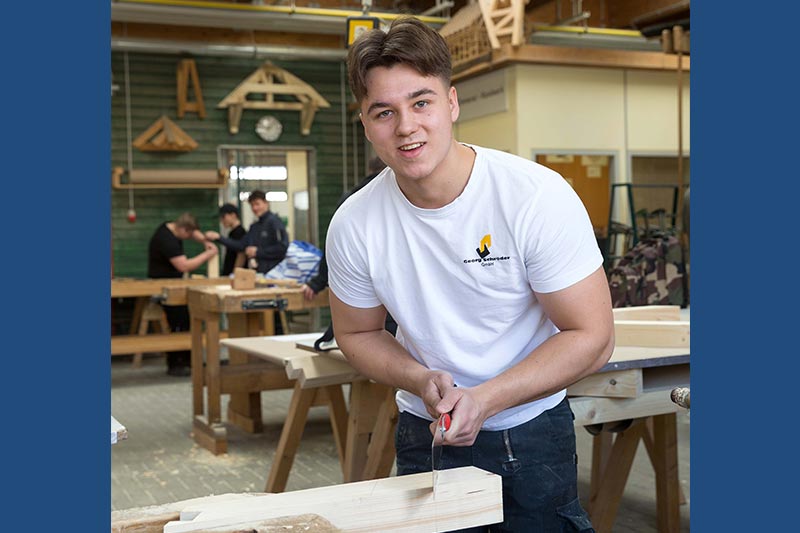 Justus Brockmann übt im Rahmen der überbetrieblichen Ausbildung im ersten Lehrjahr das Sägen von Schrägen - Traumberufe Zimmerer 2023