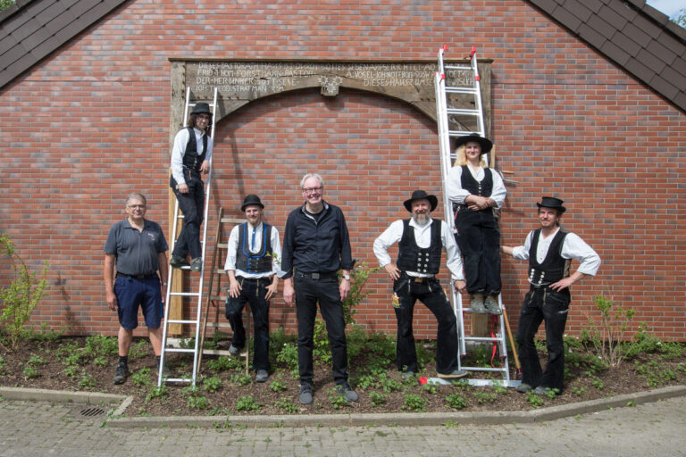 Zimmerer Team Gutwin mit Pfarrer Volker Kluft (mitte) vor dem Gebäude der Evangelischen St.-Andreas-Kirchengemeinde Ostönnen - Traumberufe Zimmerer 2025