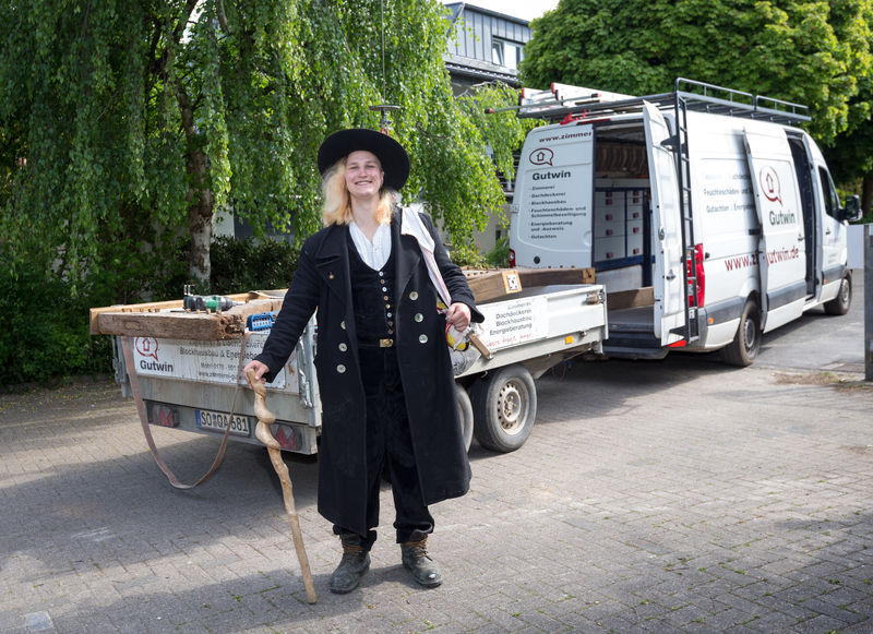 Wandergesellin Wiktoria steht in traditioneller Kluft vor dem Bulli - Traumberufe Zimmerer 2025
