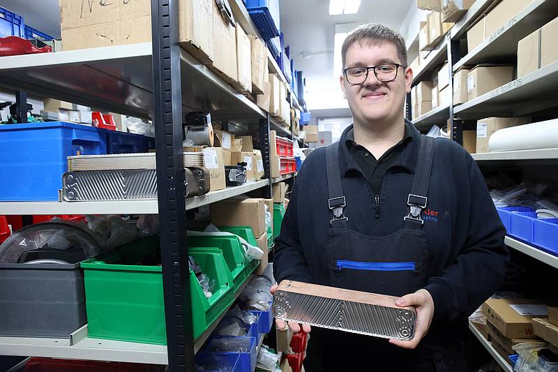 Maurice Zimmermann im Lager, mit dem Wärmetauscher in der Hand - Traumberufe Anlagenmechaniker für SHK 2024
