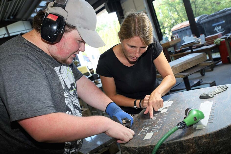 Steinmetz-Geselle Dominik Hensa spricht mit Meisterin Daniela Clever die Inschrift eines Grabsteins durch. Er mag die Arbeit mit den Gedenksteinen, hat bereits seine Ausbildung beim Natursteinhandel R. Wöhrle in Hamm gemacht. (Foto: Markus Liesegang)