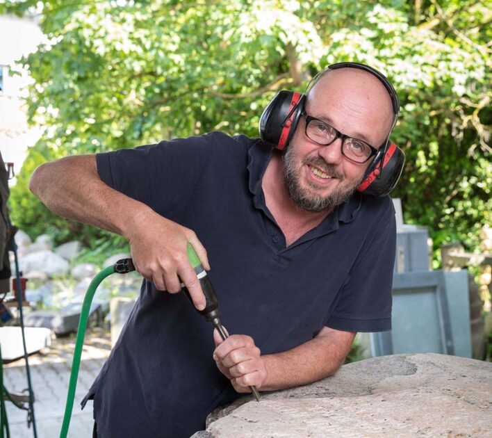 Mit einem Drucklufthammer haut Steinbildhauer Johannes Düchting die Buchstaben und Zahlen in einen skandinavischen Gneis. (Foto: Gabi Bender)