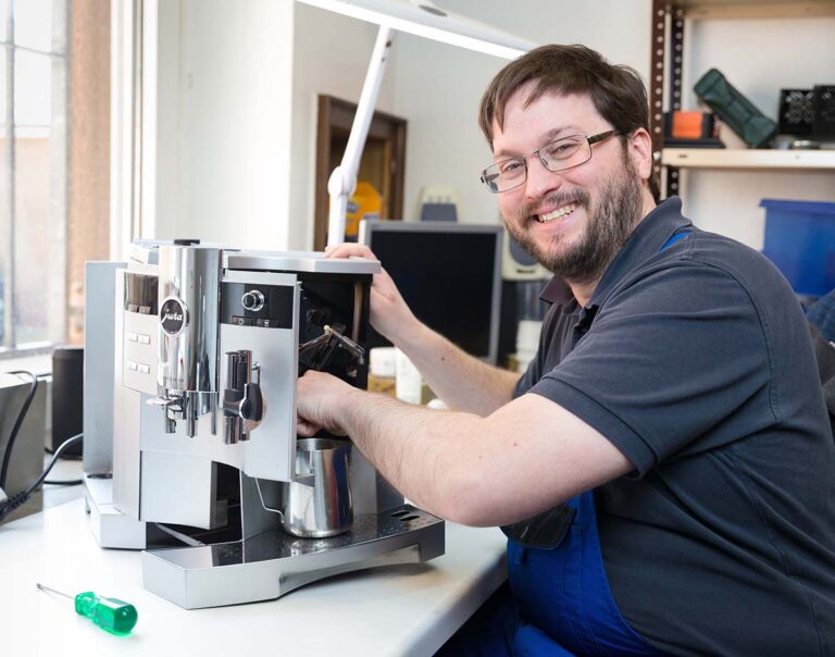 Regelmäßig repariert Eric Eckmann Kaffeevollautomaten. Bei diesem Gerät ist etwas undicht. Ein Defekt, den der Informationselektroniker gerade fachgerecht behebt. (Foto: Gabi Bender)